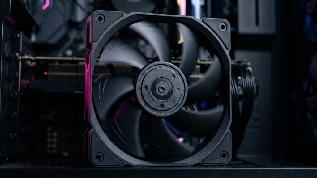 Close-up of 120mm PC case fan spinning showing blade geometry and motion blur