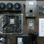 Flat-lay of RX 9070 XT PC build components including GPU, Ryzen 5 9600X, B650 motherboard, DDR5 RAM, NVMe SSD and handwritten parts list totaling $1600