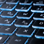 Close-up of a gaming laptop's blue backlit keyboard with the screen glowing behind it