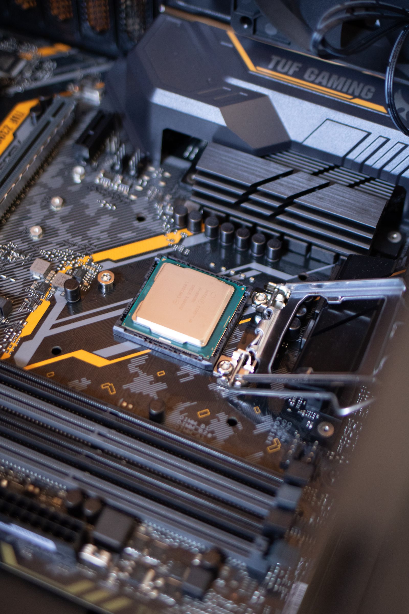Intel desktop processor seated in its open LGA socket on an ASUS TUF Gaming motherboard, with the retention lever raised