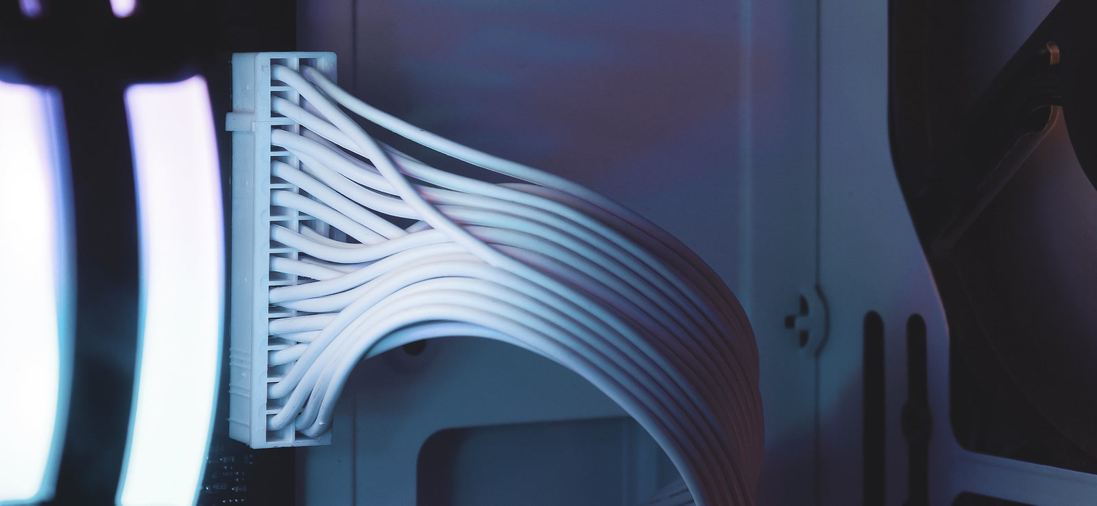 A 24-pin power cable plugged into a motherboard inside a dark PC case