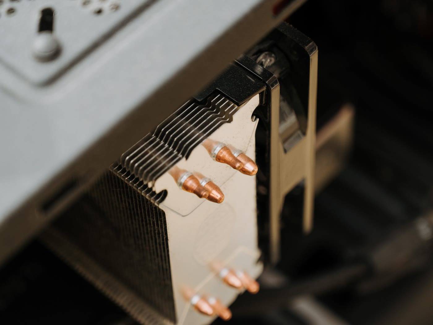 Close-up of a tower CPU cooler inside a PC case, showing its aluminium fin stack and copper heatpipe ends next to the fan